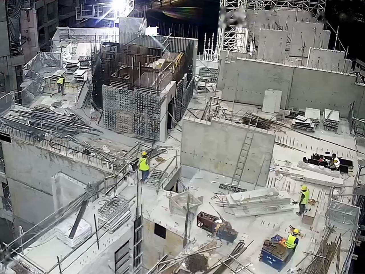 Camera over a building under construction: a worker on an upper floor near an unguarded edge.